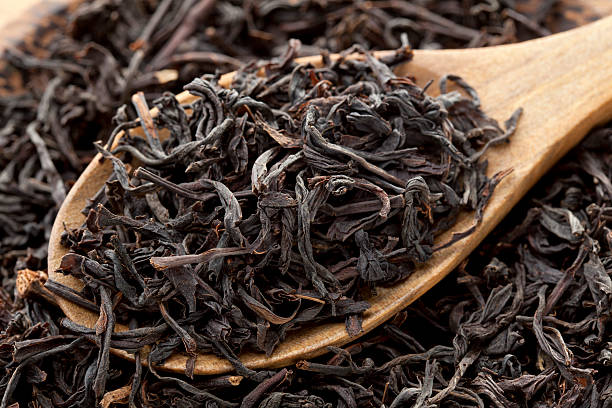 Dry tea leaves on wooden spoon